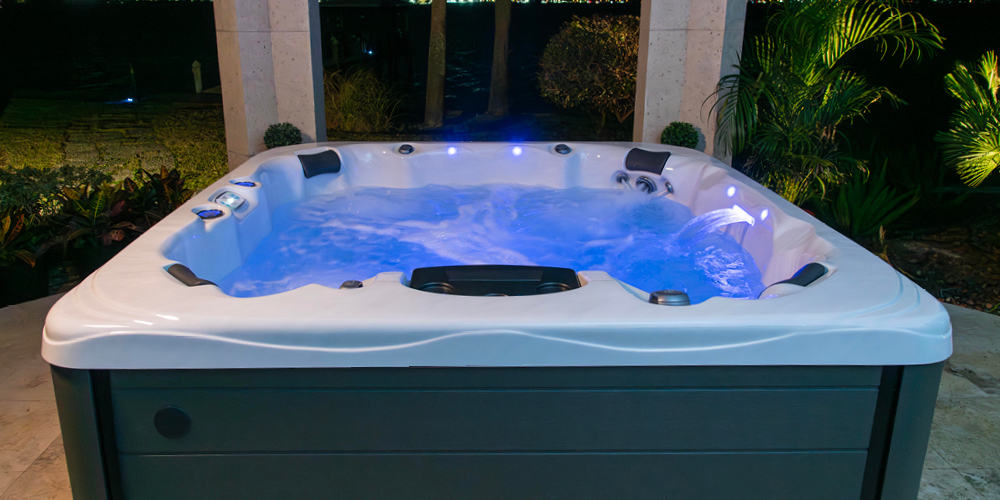 Side view of a Precision 7 hot tub at night with the led features turned on.